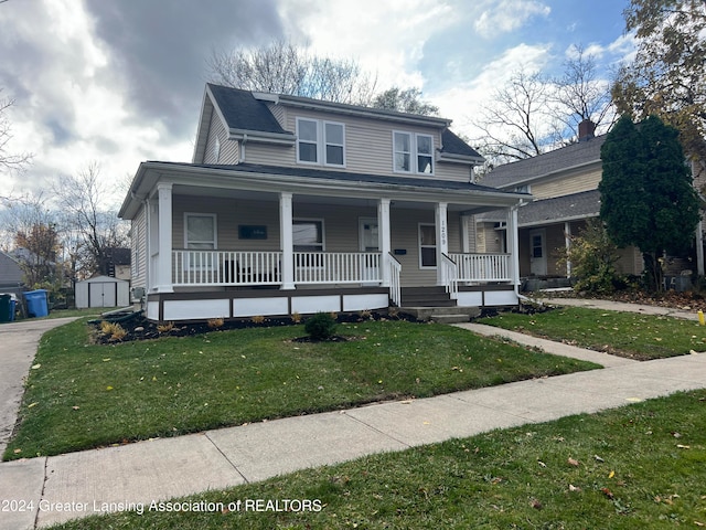 view of front of property with a front yard, a porch, and a storage unit