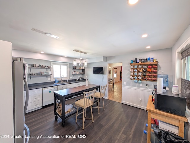 kitchen with pendant lighting, dishwasher, sink, dark hardwood / wood-style floors, and stainless steel refrigerator