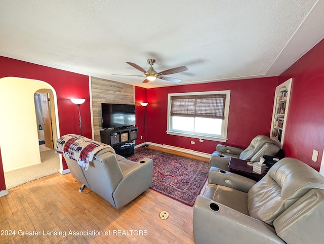 living room featuring a textured ceiling, hardwood / wood-style flooring, ceiling fan, and a baseboard heating unit