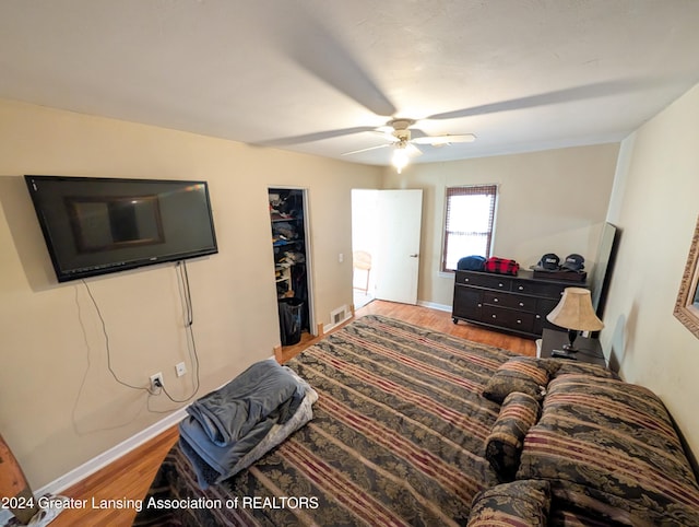 bedroom featuring hardwood / wood-style flooring, a spacious closet, a closet, and ceiling fan