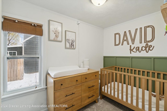 carpeted bedroom featuring a nursery area and ornamental molding