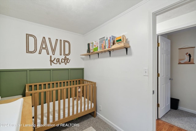 bedroom featuring hardwood / wood-style floors, a textured ceiling, crown molding, and a nursery area