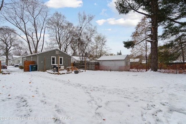 snow covered rear of property with an outdoor structure and an outdoor fire pit