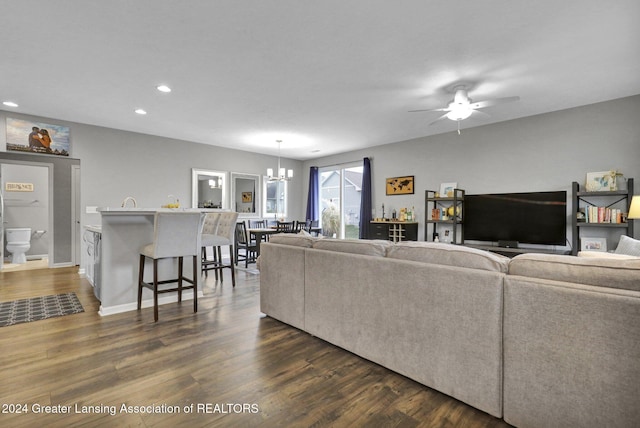 living area with baseboards, ceiling fan with notable chandelier, recessed lighting, and dark wood-style floors
