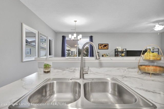 details featuring a sink, hanging light fixtures, light stone countertops, and ceiling fan with notable chandelier