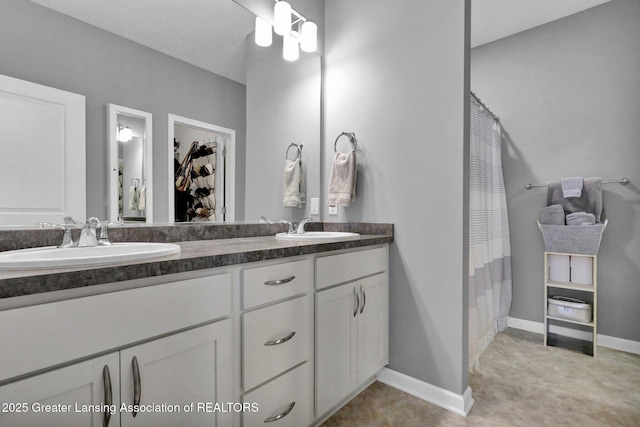 full bath with double vanity, baseboards, curtained shower, and a sink