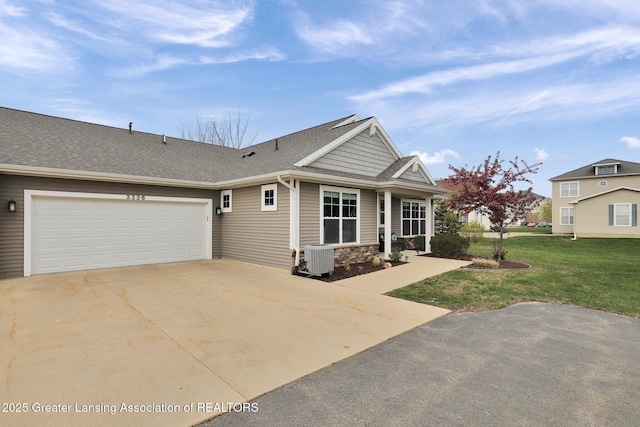 view of front of home featuring driveway, roof with shingles, a front yard, a garage, and central AC