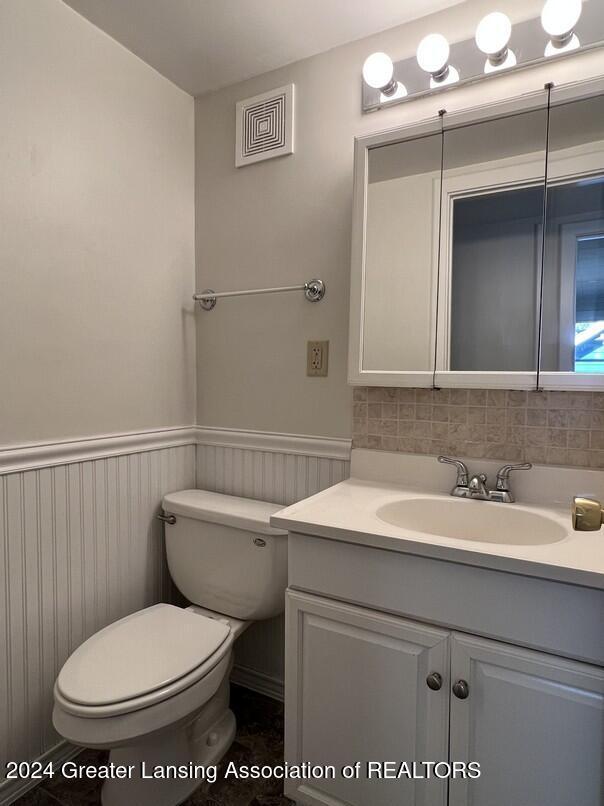 bathroom featuring vanity, toilet, and tasteful backsplash