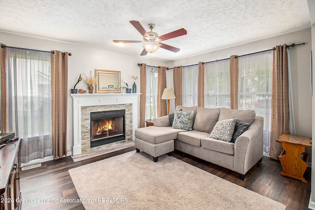 living room featuring a fireplace, a textured ceiling, dark hardwood / wood-style floors, and ceiling fan