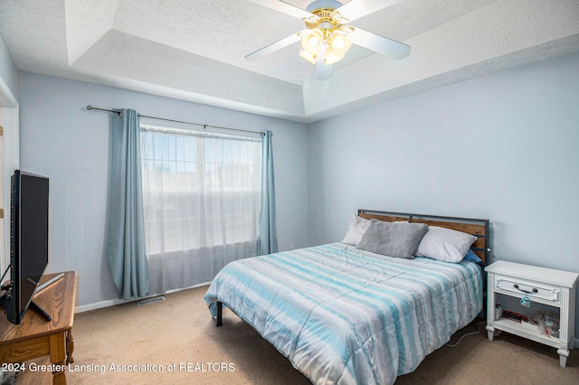 bedroom with carpet, ceiling fan, and a raised ceiling