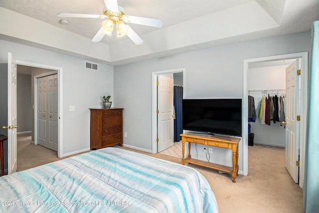 carpeted bedroom featuring a closet, a raised ceiling, and ceiling fan