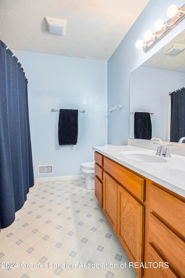 bathroom with a textured ceiling, vanity, and toilet