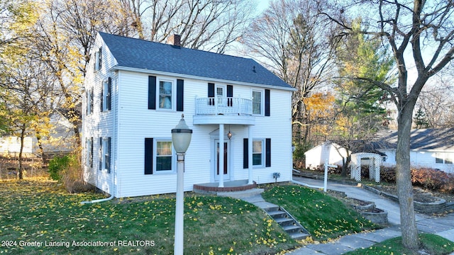 colonial-style house with a balcony and a front lawn