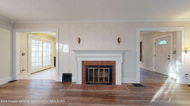 unfurnished living room featuring a brick fireplace, crown molding, plenty of natural light, and hardwood / wood-style flooring