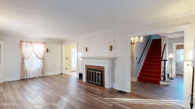 unfurnished living room featuring hardwood / wood-style floors, a notable chandelier, ornamental molding, and a fireplace