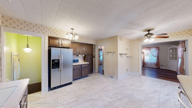 kitchen with pendant lighting, ceiling fan with notable chandelier, sink, light wood-type flooring, and appliances with stainless steel finishes