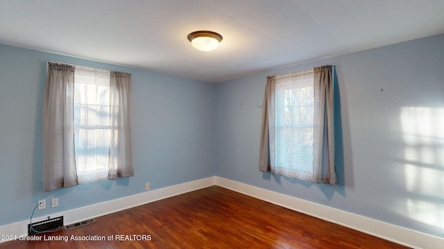 spare room with wood-type flooring and a healthy amount of sunlight