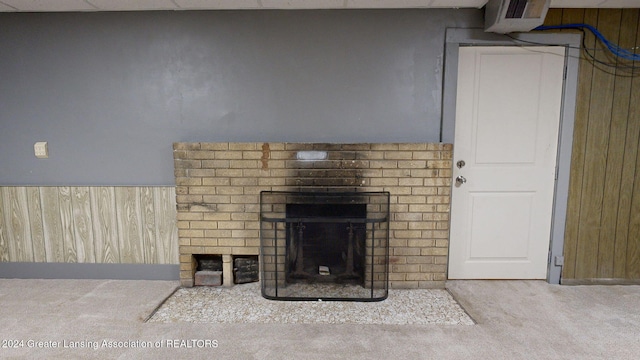 interior details with carpet flooring, wooden walls, and a brick fireplace