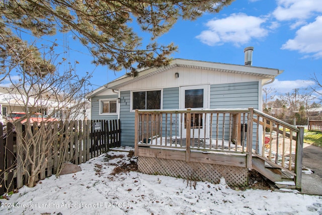 snow covered rear of property featuring a wooden deck