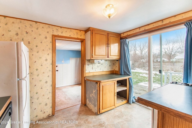 kitchen featuring dishwashing machine, white fridge, light colored carpet, and crown molding