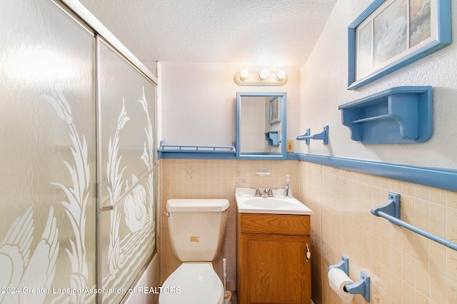 bathroom with a textured ceiling, toilet, and tile walls