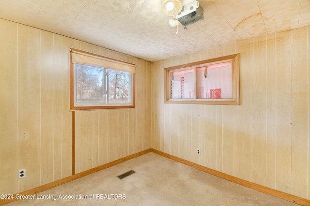 empty room featuring light colored carpet and wooden walls