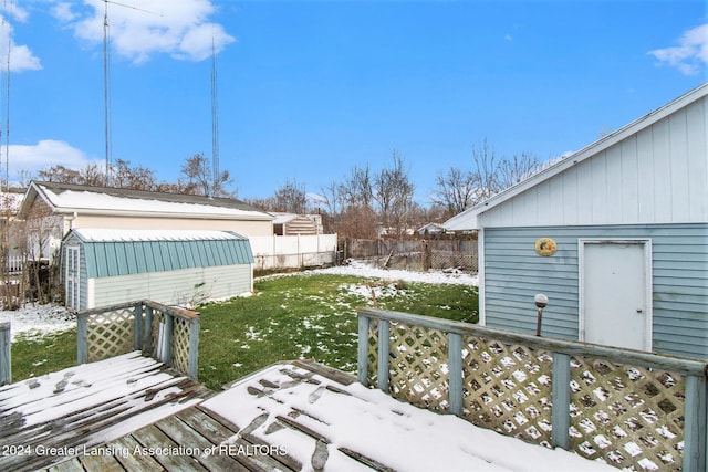 yard layered in snow featuring a deck and a storage shed