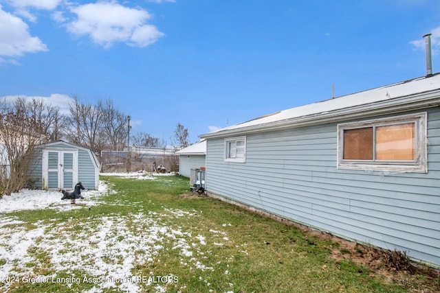 yard layered in snow featuring a storage shed