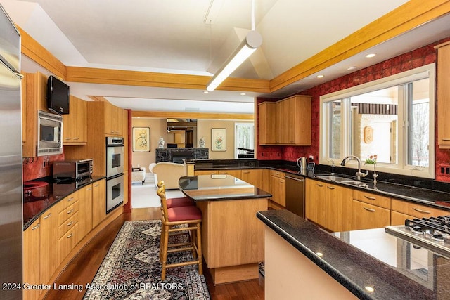 kitchen featuring a center island, dark wood-type flooring, sink, appliances with stainless steel finishes, and a kitchen bar