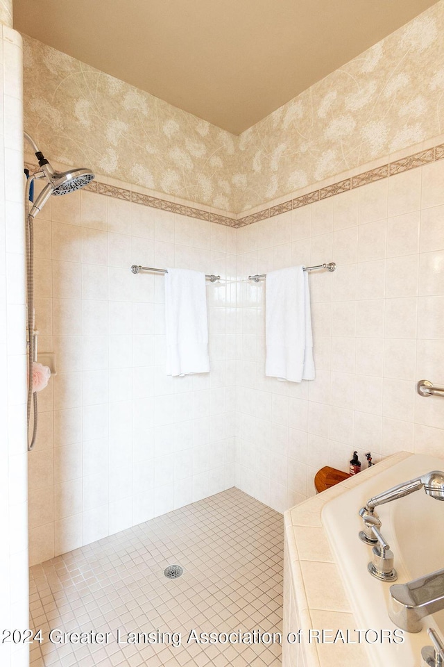 bathroom featuring a tile shower, sink, and tile walls