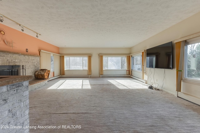 unfurnished living room with light carpet, a textured ceiling, track lighting, and a healthy amount of sunlight