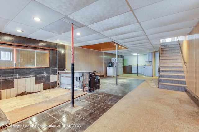 basement with white refrigerator and a drop ceiling