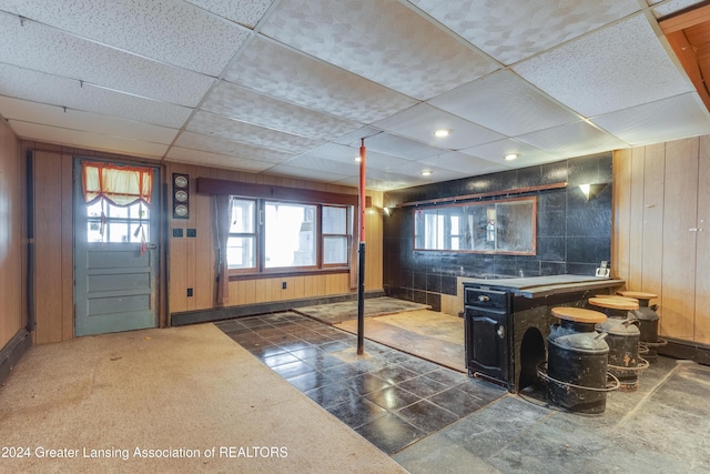 interior space with a drop ceiling and wood walls