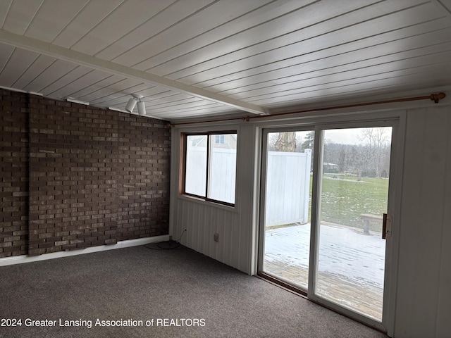 unfurnished sunroom featuring beamed ceiling and plenty of natural light