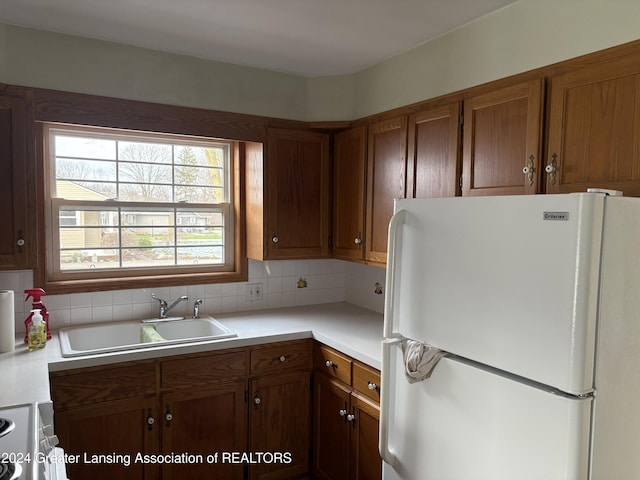 kitchen with decorative backsplash, white refrigerator, and sink