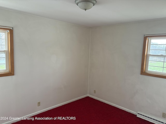 carpeted empty room with baseboard heating and a healthy amount of sunlight