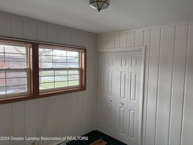 unfurnished bedroom with wood walls and a closet