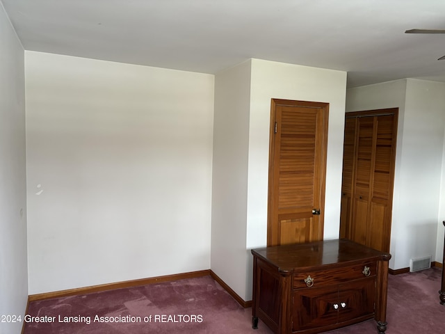 unfurnished bedroom with dark carpet and a closet