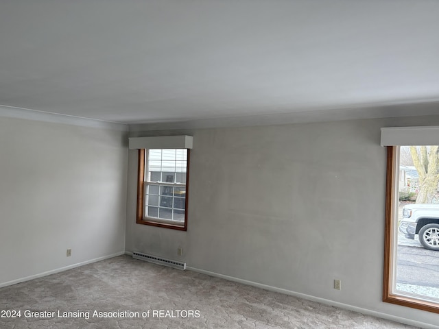 unfurnished room featuring light colored carpet, crown molding, baseboard heating, and a healthy amount of sunlight