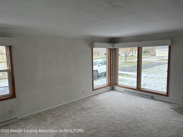 carpeted empty room with a wealth of natural light and a baseboard heating unit