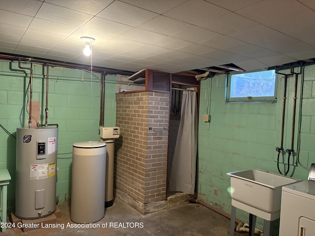 utility room featuring electric water heater, washer / clothes dryer, and sink