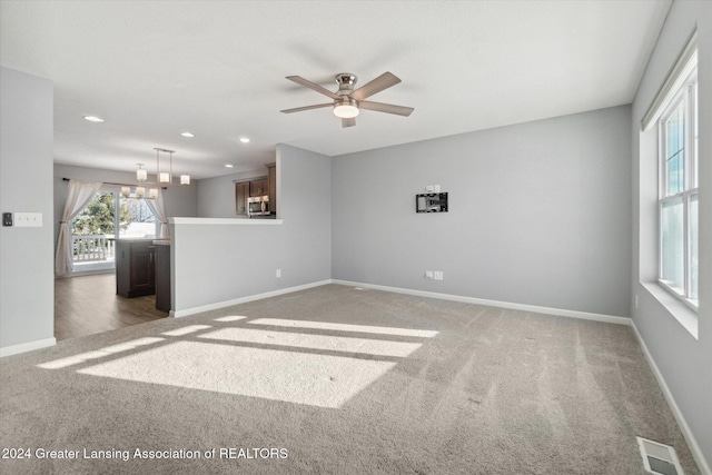 unfurnished room featuring dark carpet and ceiling fan with notable chandelier