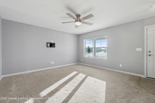 carpeted spare room with ceiling fan