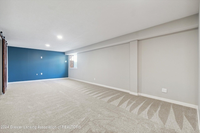 basement featuring a barn door and carpet