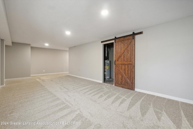 spare room featuring carpet flooring, a barn door, and gas water heater