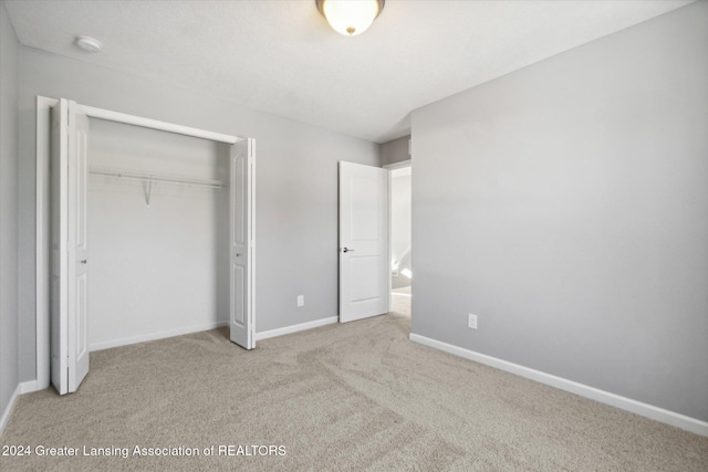 unfurnished bedroom featuring light colored carpet and a closet