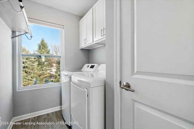 laundry area with a healthy amount of sunlight, cabinets, wood-type flooring, and washing machine and dryer