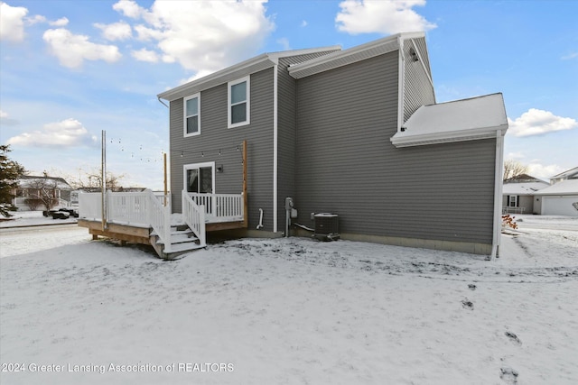 snow covered rear of property with a deck and cooling unit