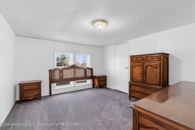 misc room featuring dark colored carpet and a textured ceiling