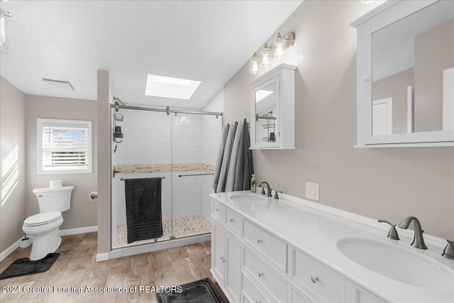 bathroom with vanity, wood-type flooring, walk in shower, and a skylight